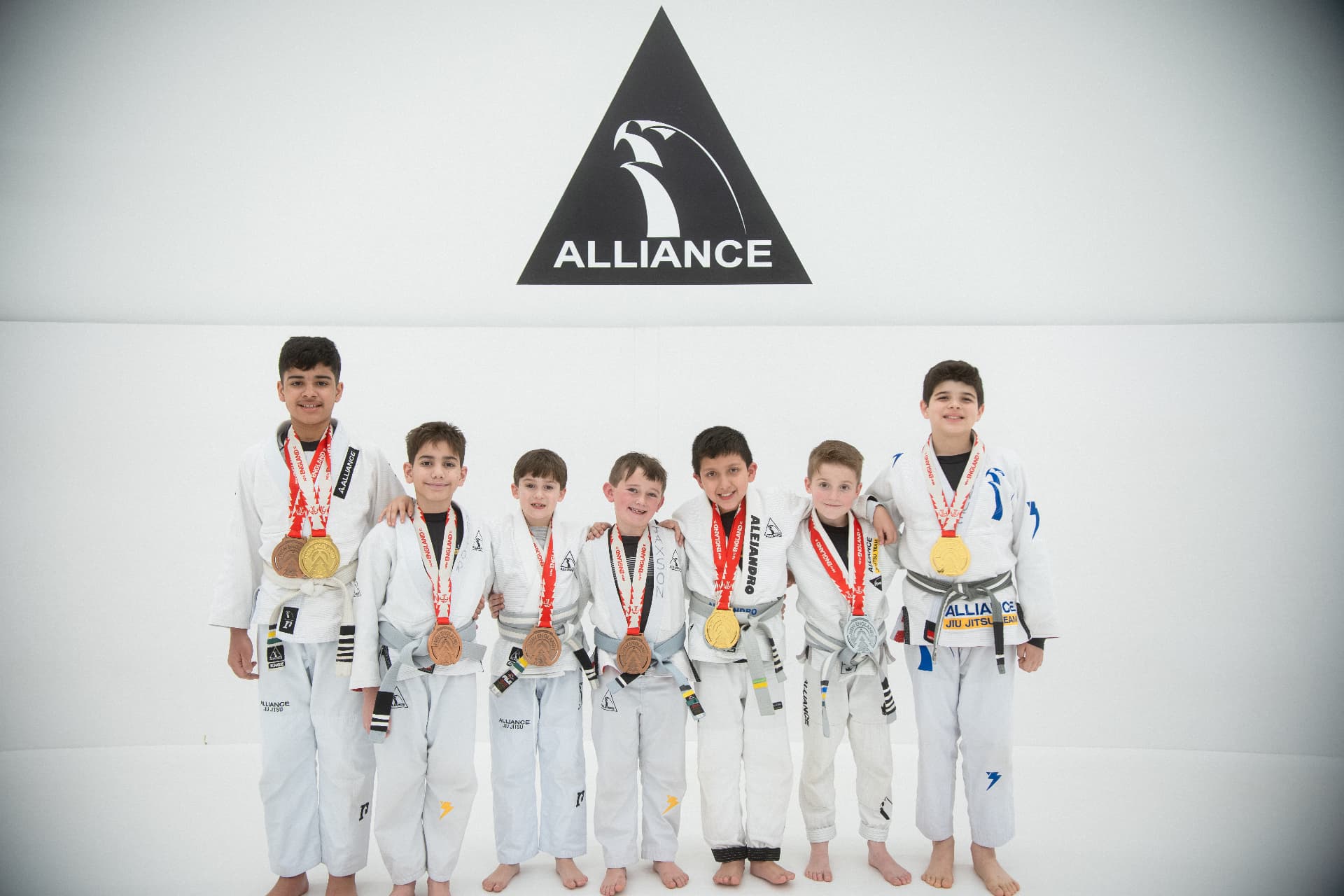 Kids team with medals in front of the Alliance logo wall
