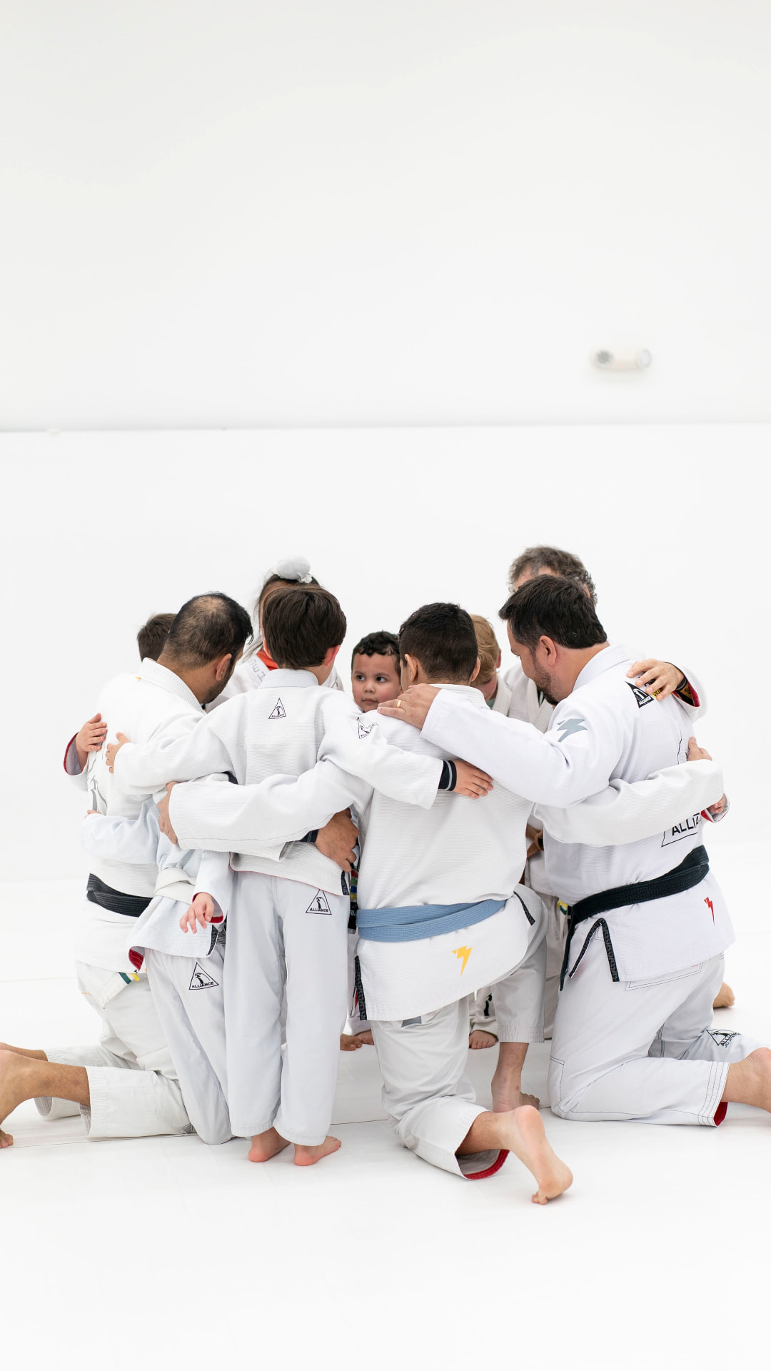 Students and coaches in a team huddle on the mat