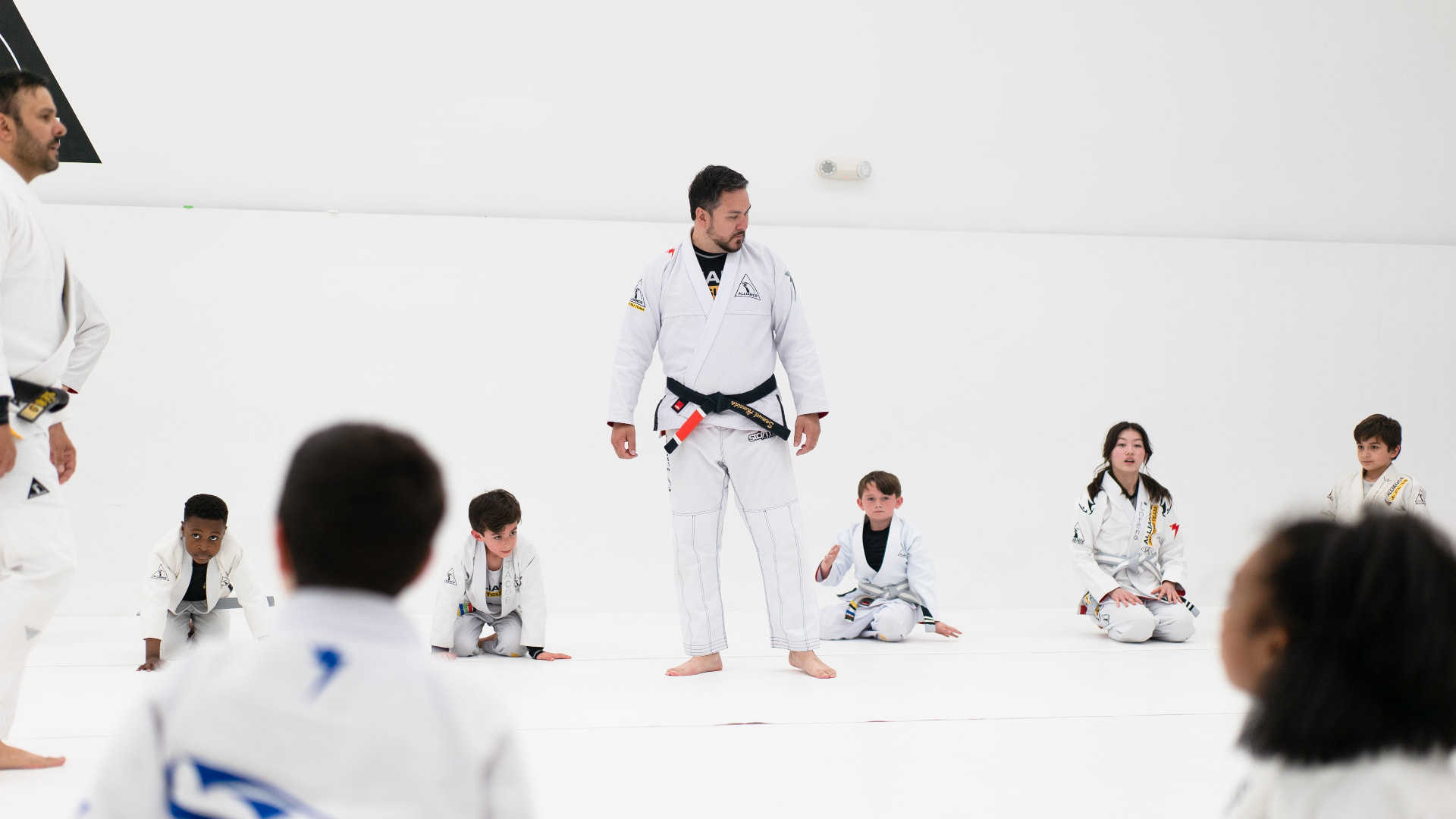 Instructor teaching a kids class on the academy mats