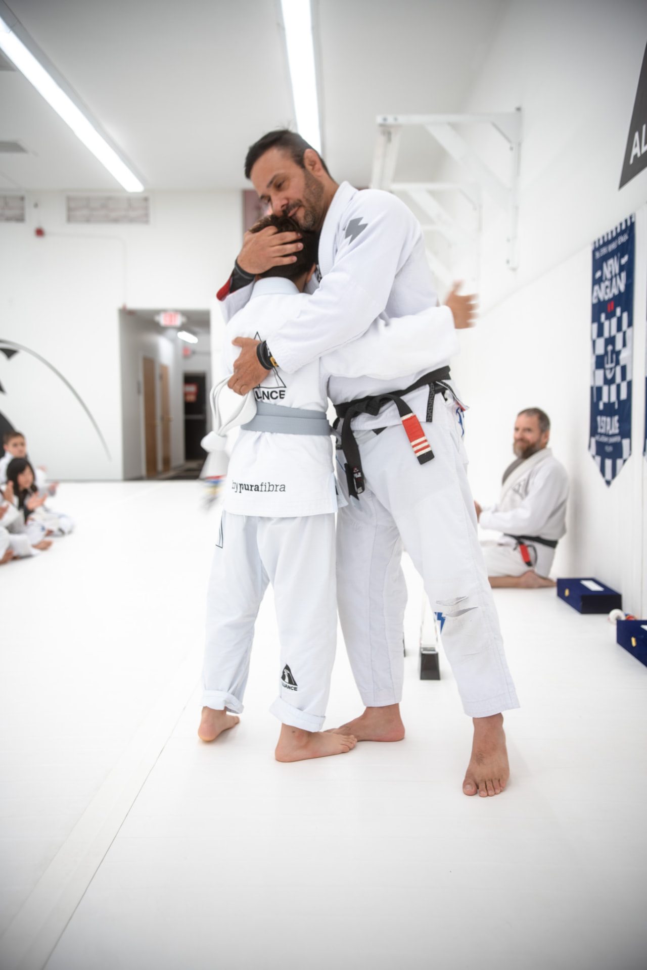 Jiu-jitsu instructor congratulating a young student on the mat